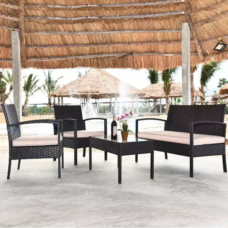 Juego de muebles de conversación de ratán para patio Costway de 4 piezas con asiento acolchado y mesa de cristal